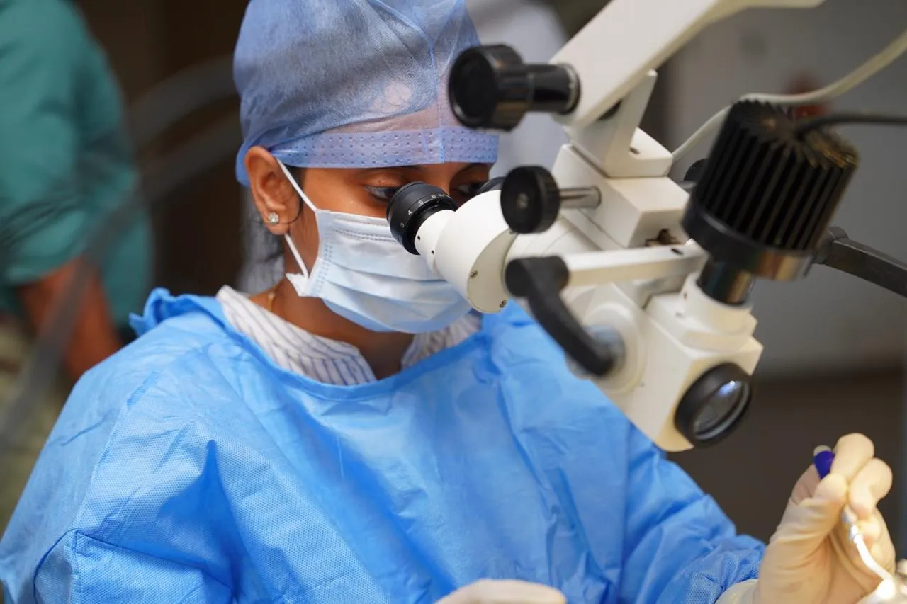 Dr. Trisha Srivastava operating under a surgical microscope